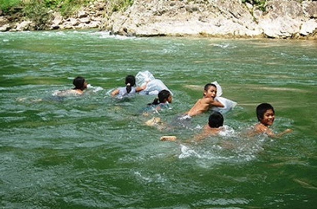 Children between grade 1 and 5 swim across this 20 meter deep river to get to school at the Trong Hoa commune