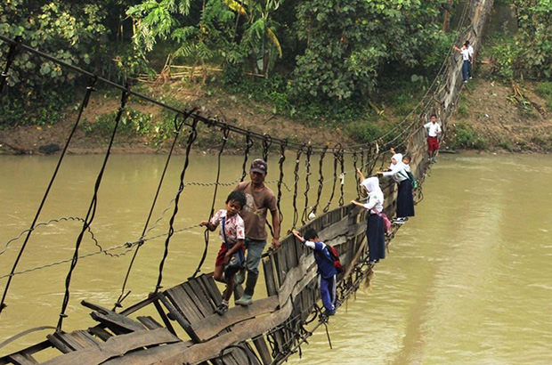 To get to school, children from the village of Sanghiang Tanjung traverse the Ciberang River via this collapsed suspension bridge